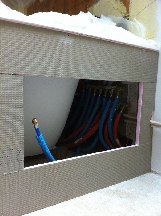 Un tas de tuyaux sortent d'un trou dans le mur