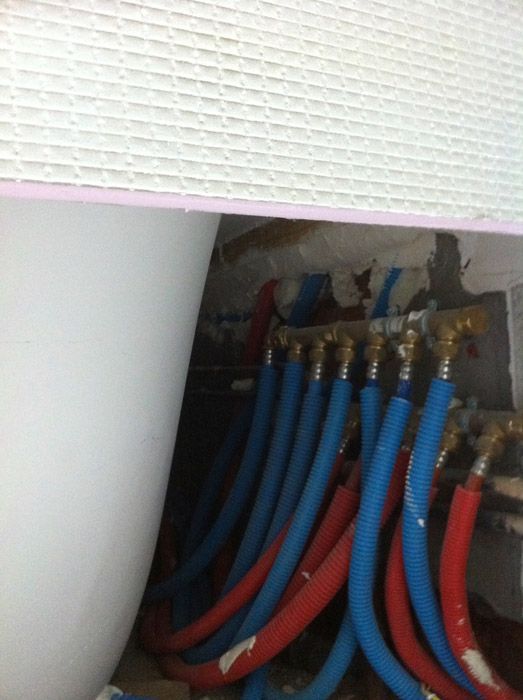 Un tas de tuyaux bleus et rouges sont reliés à un mur