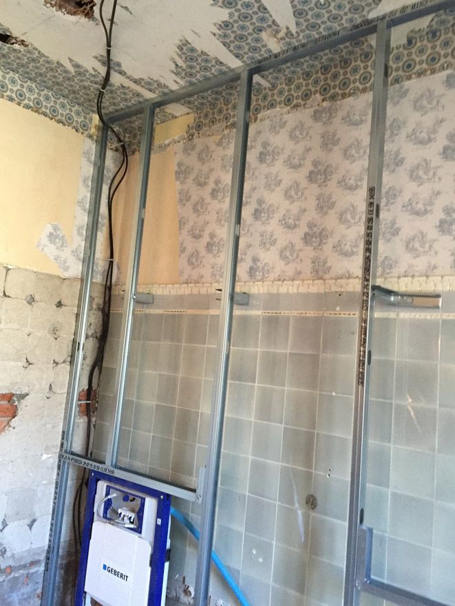Une salle de bain est en cours de rénovation et il y a des toilettes dans le mur.