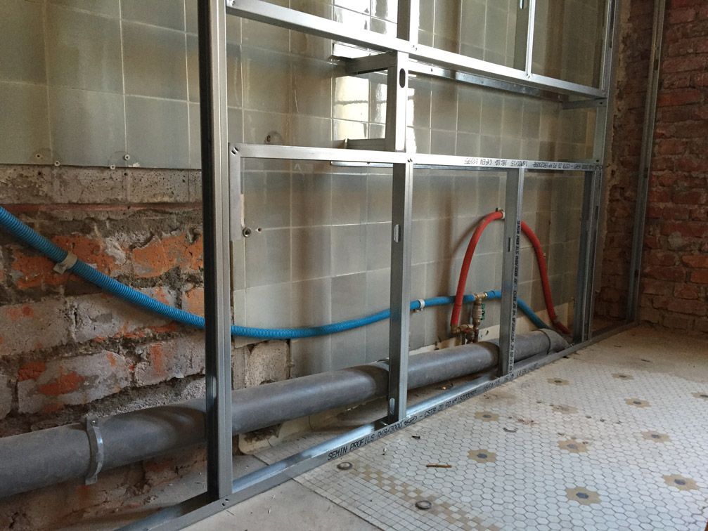 Une pièce avec un mur de briques et des tuyaux qui en sortent.