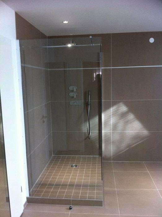 Une salle de bain avec une douche à l'italienne avec une porte vitrée