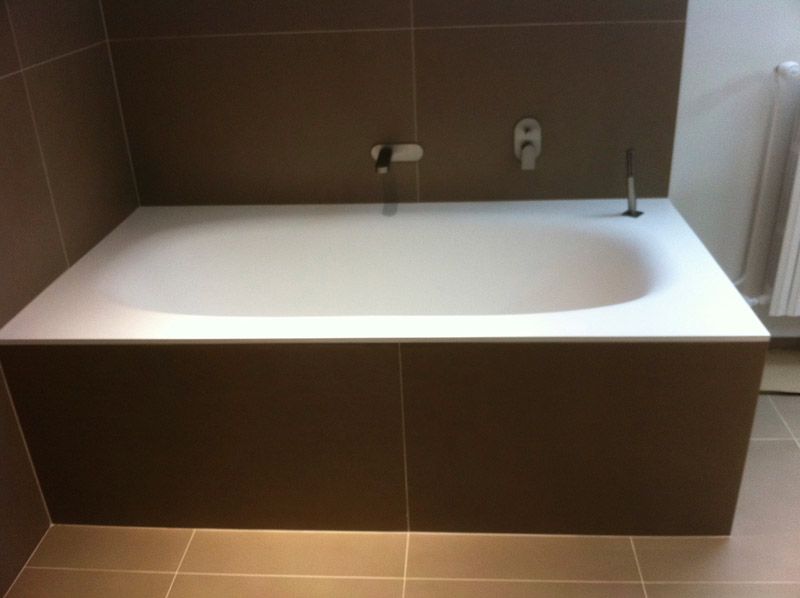Une baignoire dans une salle de bain avec du carrelage marron