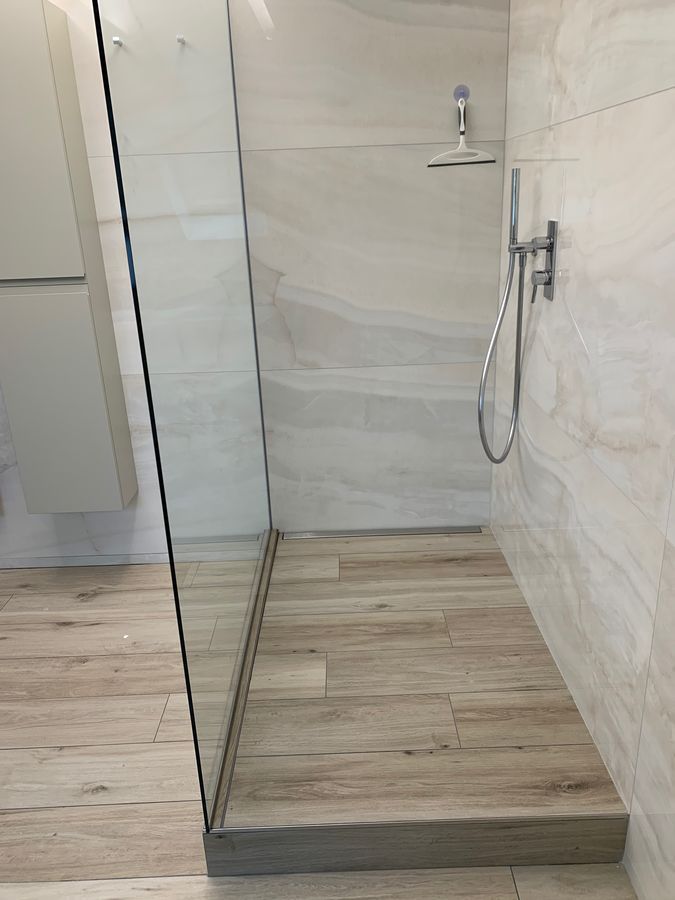 Une salle de bain avec douche à l'italienne et pommeau de douche.