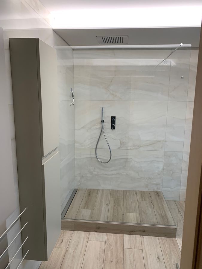 Une salle de bain avec douche à l'italienne et un parquet au sol.