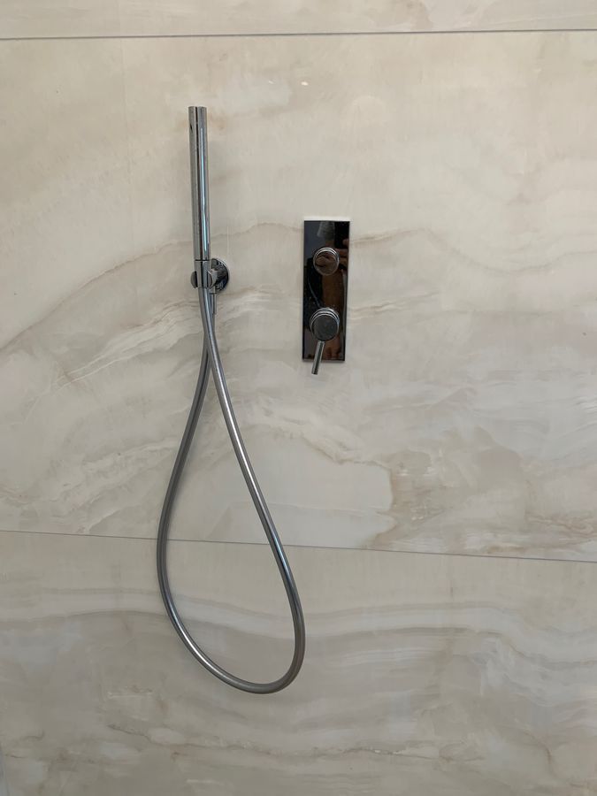 Une pomme de douche avec un tuyau attaché est suspendue à un mur.