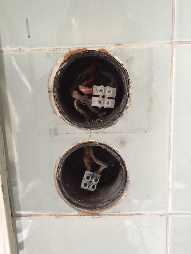 Deux trous dans un mur avec des fils électriques qui en sortent.