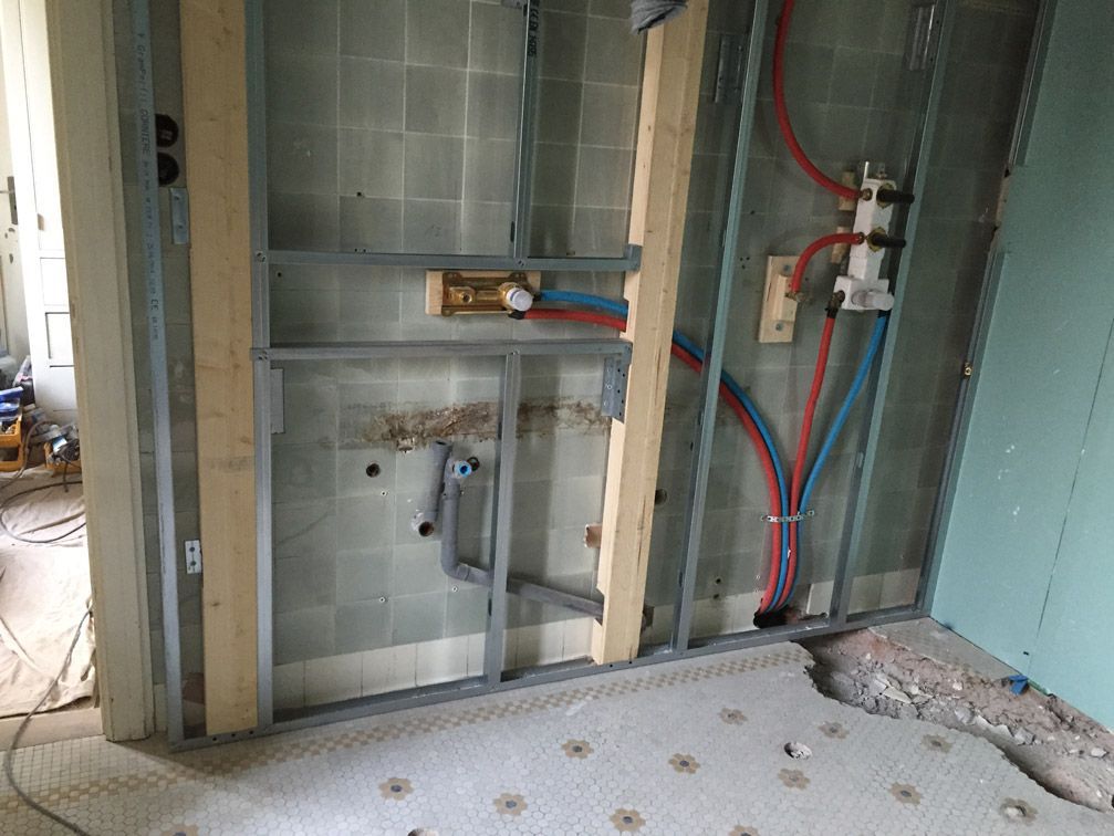 Une salle de bain en construction avec des tuyaux sortant du mur