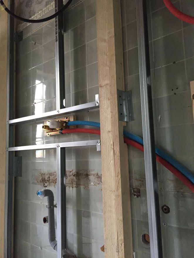 Une salle de bain en construction avec des tuyaux sortant du mur.
