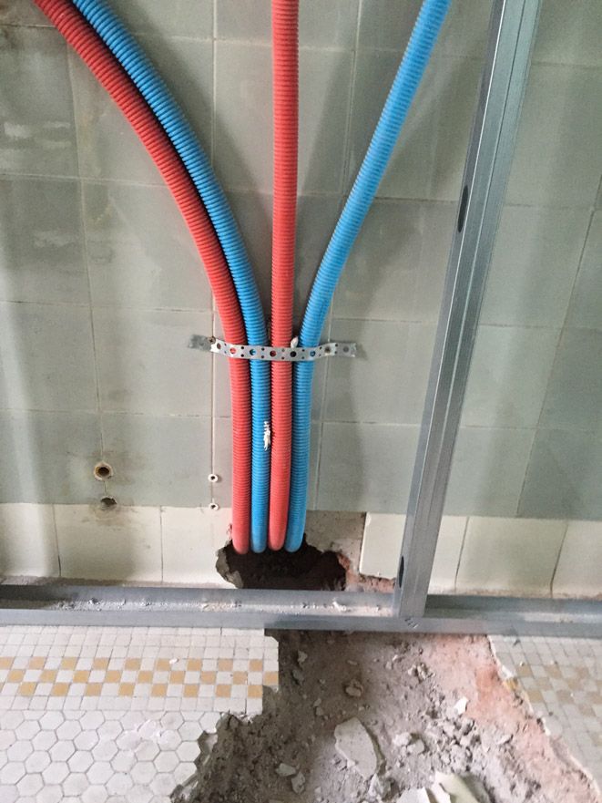 Un tas de tuyaux rouges et bleus sont suspendus à un mur.