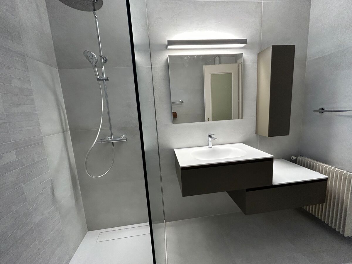 Une salle de bain avec lavabo, miroir et douche.