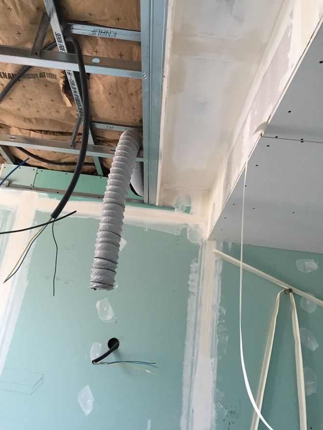 Un tuyau est suspendu au plafond d'une pièce en construction.