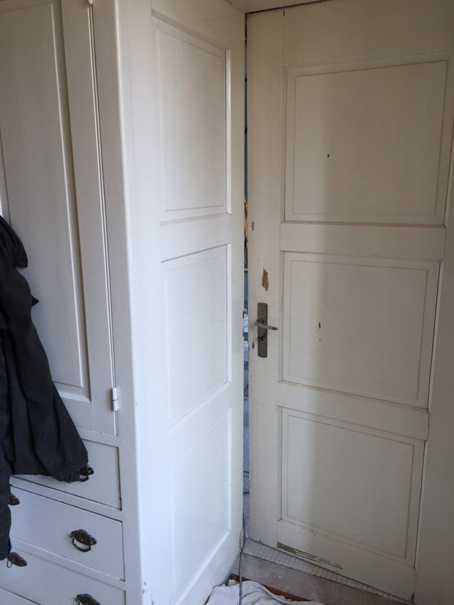 Une porte blanche est ouverte dans une pièce à côté d'une commode.