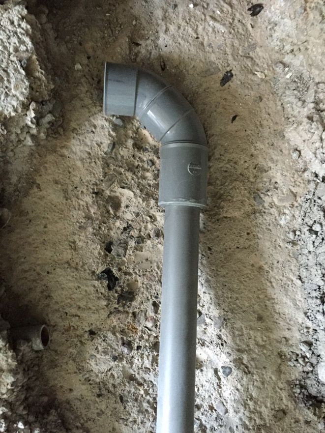 Un tuyau est posé dans la terre à côté d'un mur en béton.