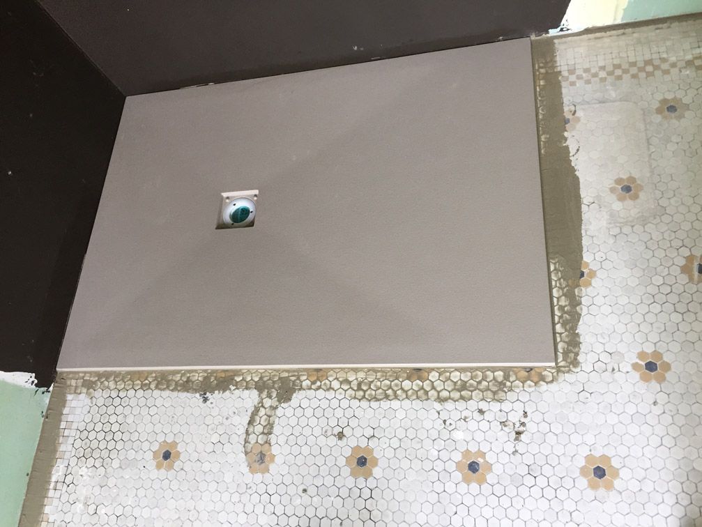 Une cabine de douche est en cours de construction sur un sol carrelé.
