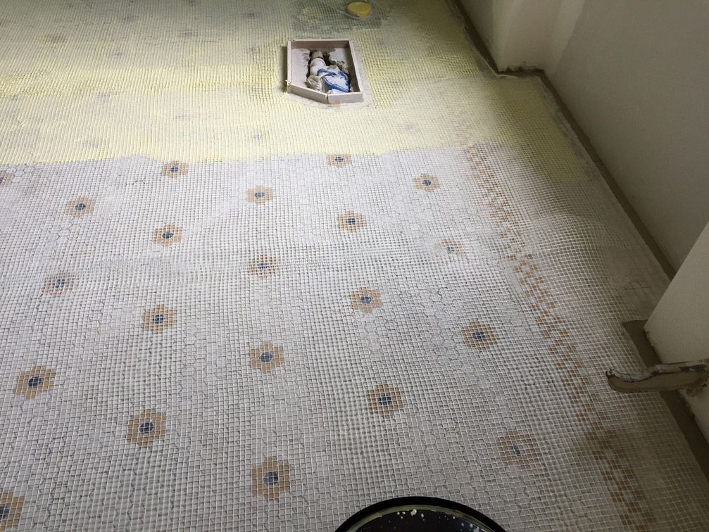 Un sol en mosaïque est en cours d'installation dans une salle de bain.
