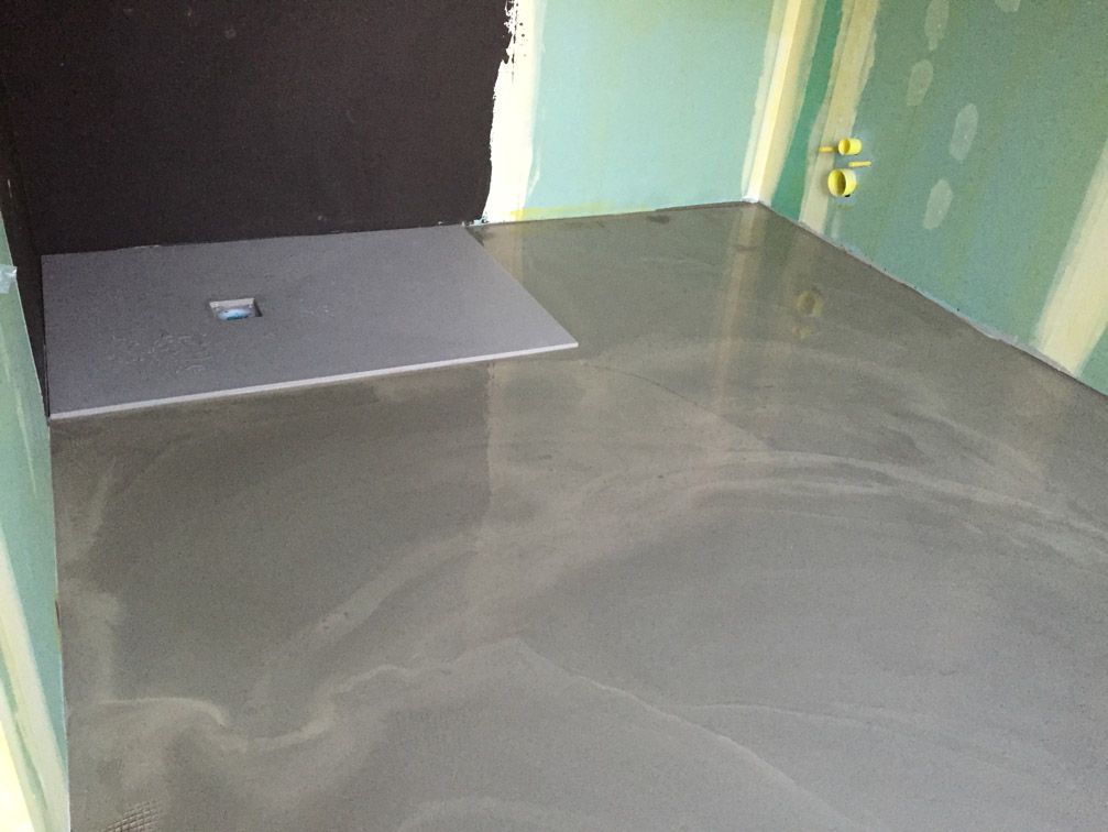 Une salle de bain avec un sol en béton et une cabine de douche