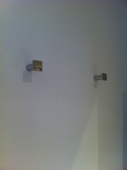 Deux crochets à serviettes sont accrochés sur un mur blanc.