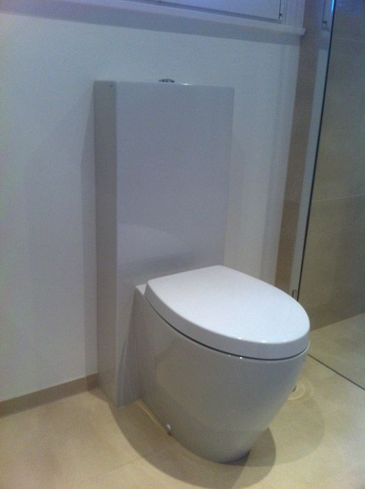 Des toilettes blanches sont installées dans une salle de bain à côté d'une fenêtre.