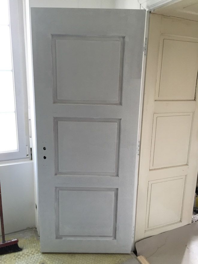 Une porte blanche se trouve dans une pièce à côté d'une fenêtre.