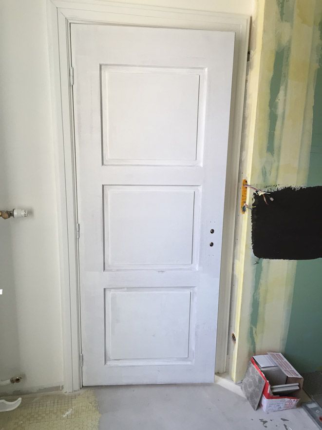 Une porte blanche se trouve dans une pièce à côté d'un mur.