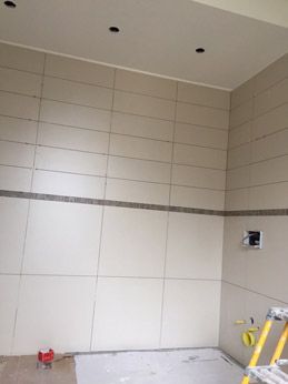 Une salle de bain avec du carrelage blanc et une échelle jaune