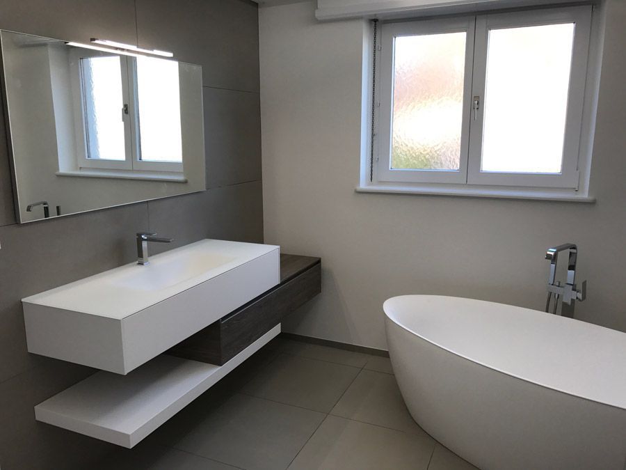 Une salle de bain avec baignoire, lavabo, miroir et fenêtre.