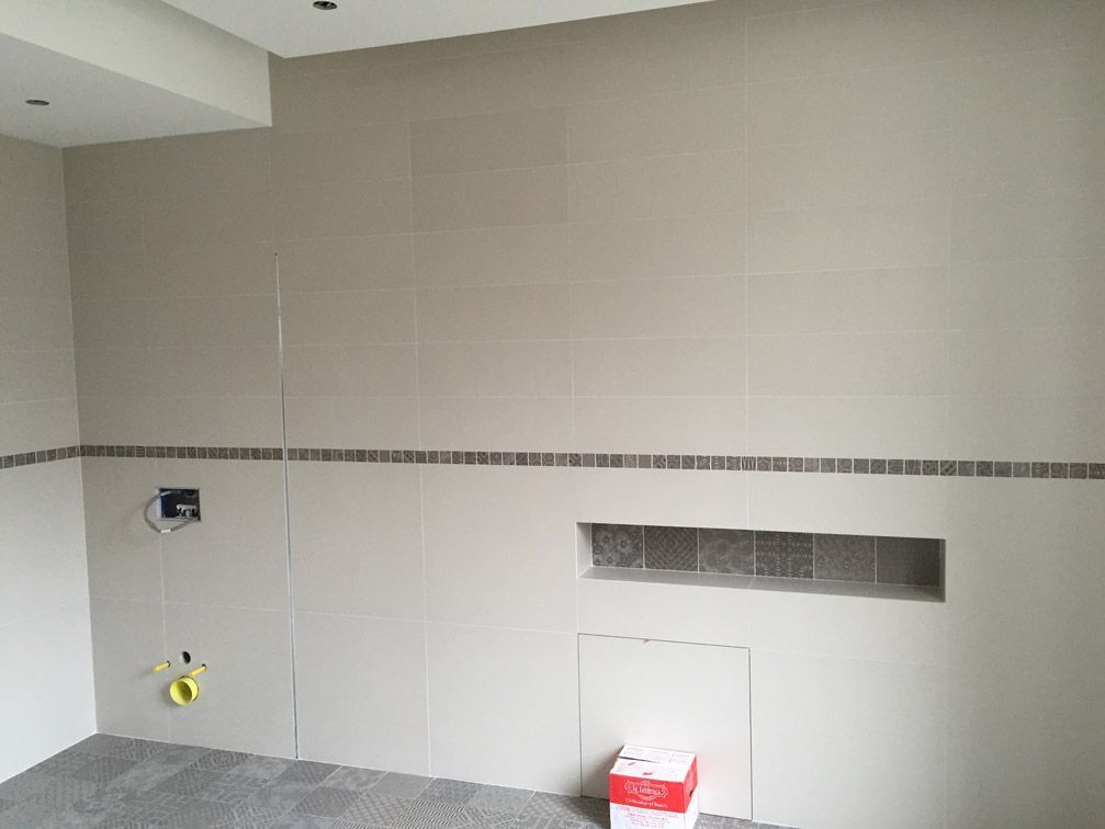 Une salle de bain avec des murs carrelés et une niche dans le mur.