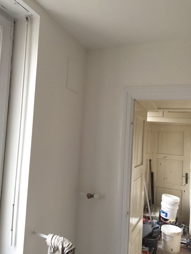 Une pièce blanche avec une fenêtre et un pot de peinture sur le sol.