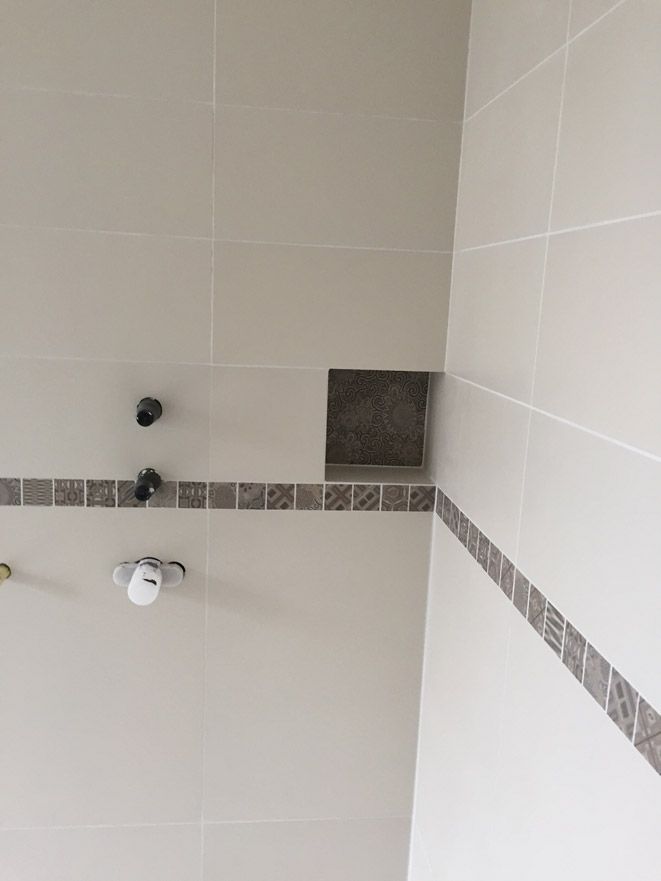 Une salle de bain avec une pomme de douche et un porte-savon au mur.