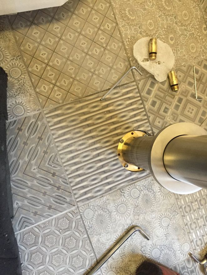 Une personne se tient debout sur un sol carrelé à côté d'un tuyau.