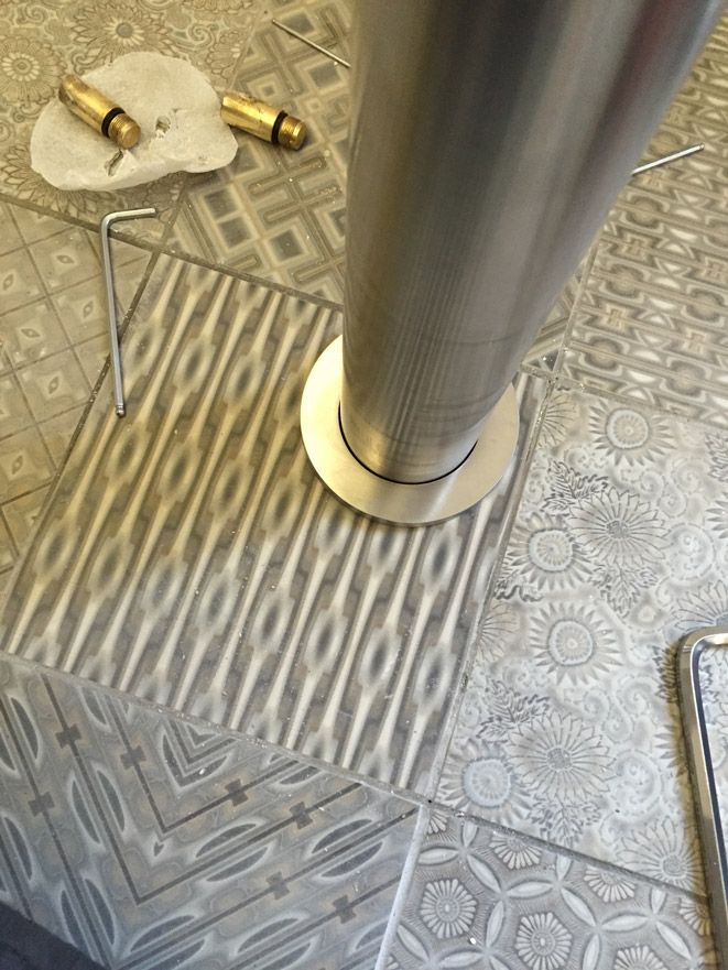 Un tuyau en acier inoxydable est posé sur un sol carrelé.