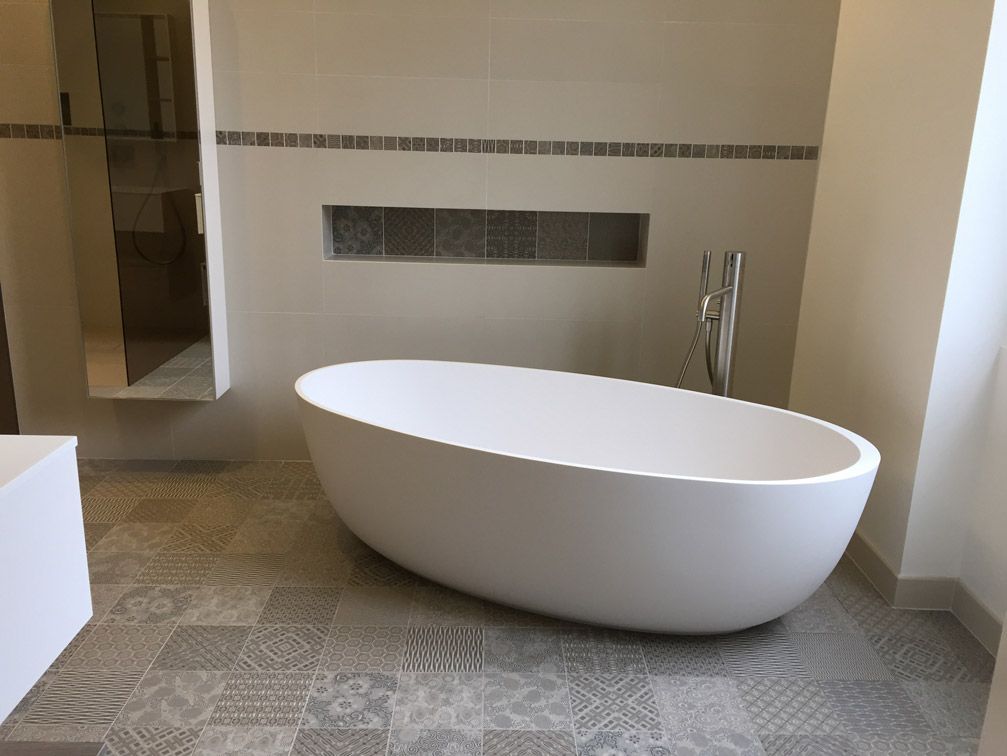 Une baignoire blanche est posée dans une salle de bain à côté d'une douche.