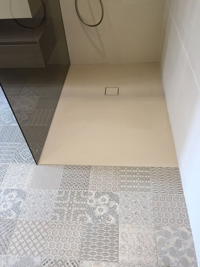 Une cabine de douche avec un sol carrelé dans une salle de bain.