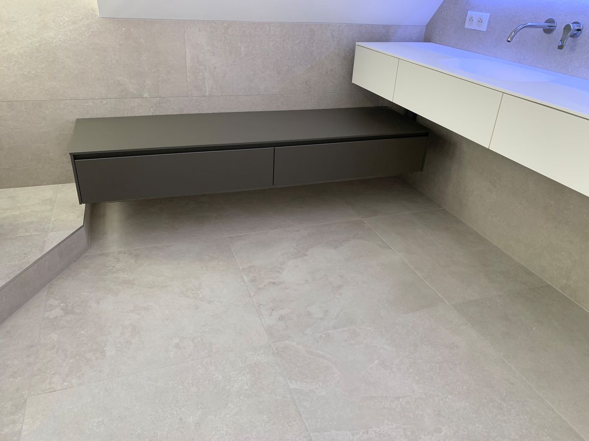 Une salle de bain avec un lavabo, un miroir et un banc.