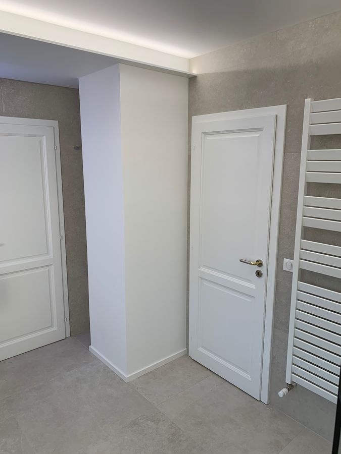 Une salle de bain avec deux portes blanches et un porte-serviettes.