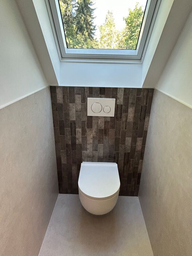 Des toilettes dans une salle de bain avec un puits de lumière au-dessus.