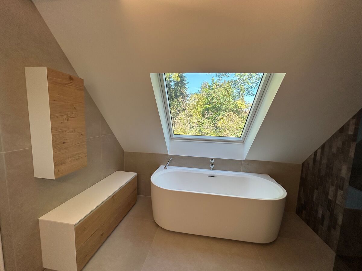 Une salle de bain avec une baignoire et un puits de lumière au-dessus.