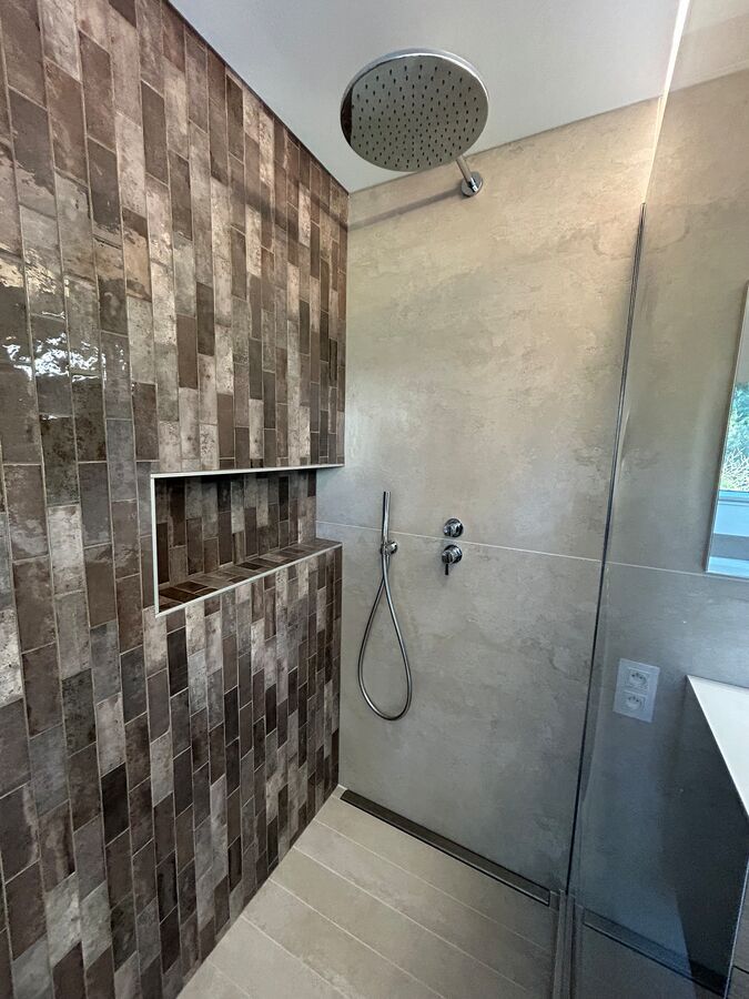 Une salle de bain avec douche à l'italienne et pommeau de douche.