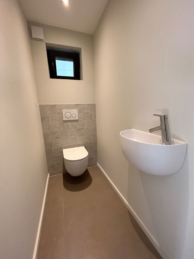 Une salle de bain avec WC, lavabo et fenêtre.