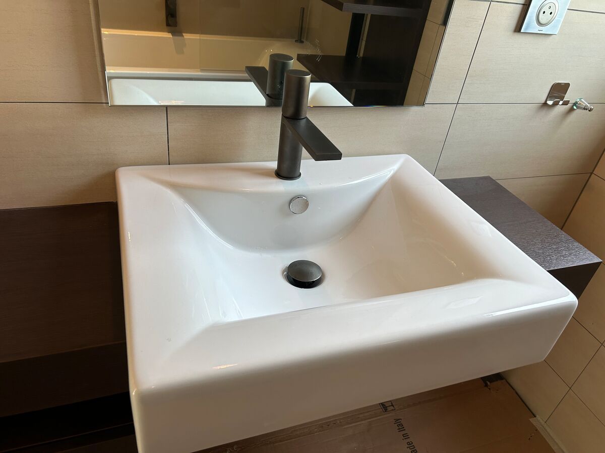 Un lavabo de salle de bain avec un robinet noir et un miroir