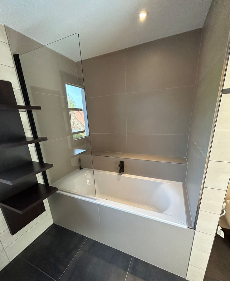 Une salle de bain avec baignoire et porte de douche en verre.