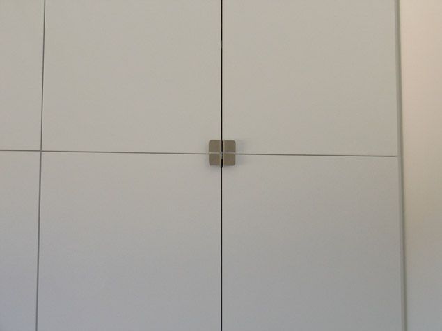 Un gros plan d'une porte blanche avec une poignée carrée.