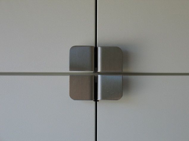 Un gros plan d'une poignée de porte en acier inoxydable sur une armoire blanche