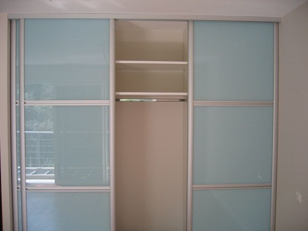 Un placard avec portes coulissantes en verre et étagères