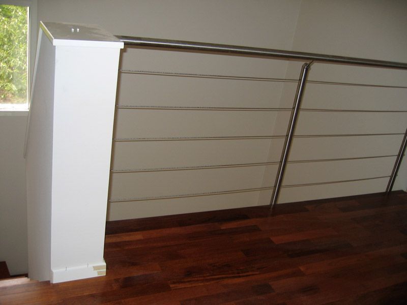 Un escalier avec une rampe en acier inoxydable et un plancher en bois