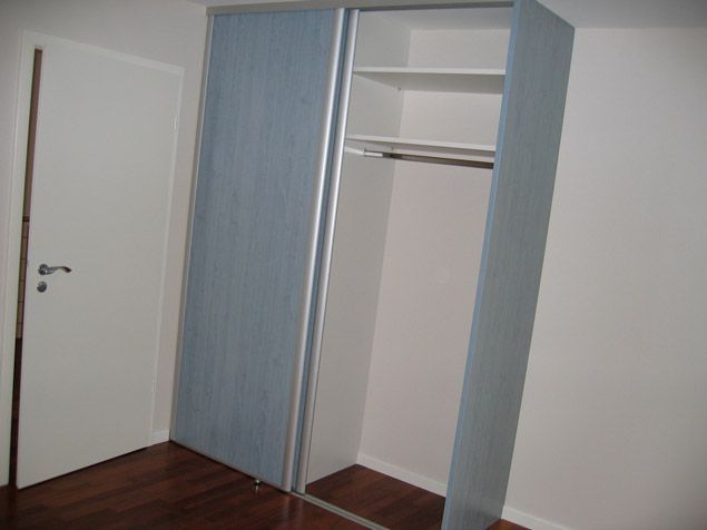 Un placard avec portes coulissantes et étagères dans une pièce