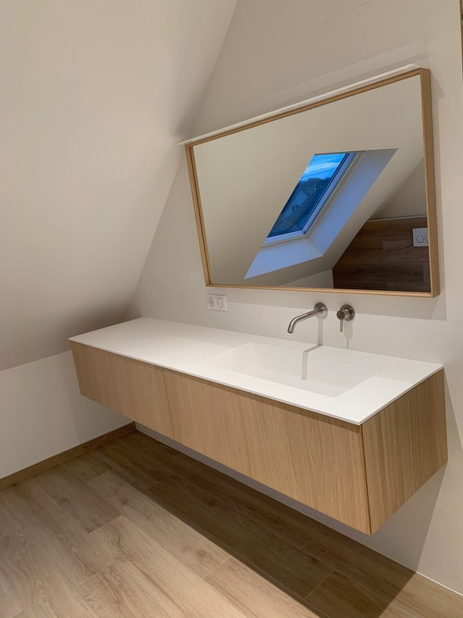 Une salle de bain avec lavabo, miroir et puits de lumière.