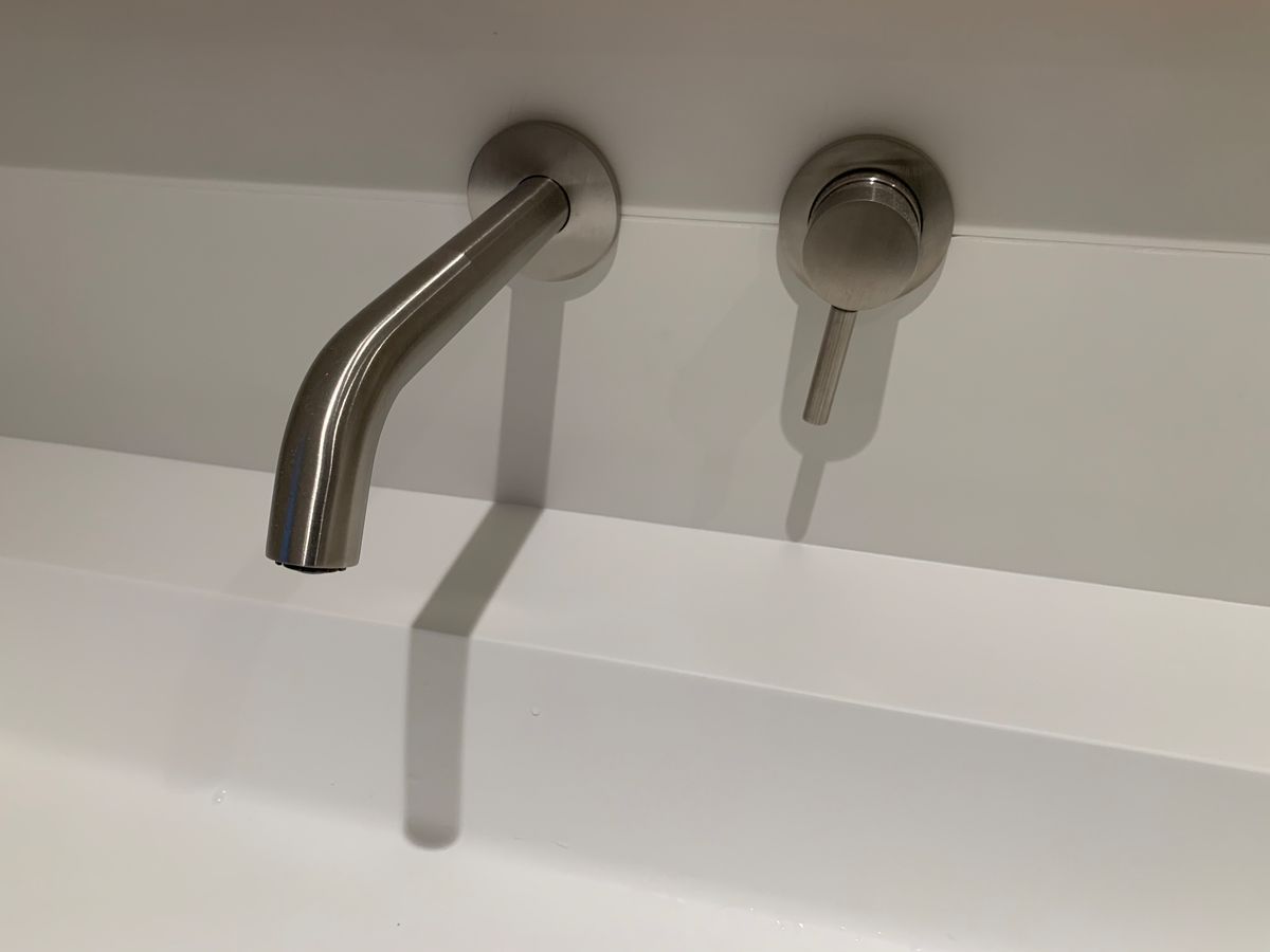 Un lavabo de salle de bain avec un robinet et une ombre sur le mur.