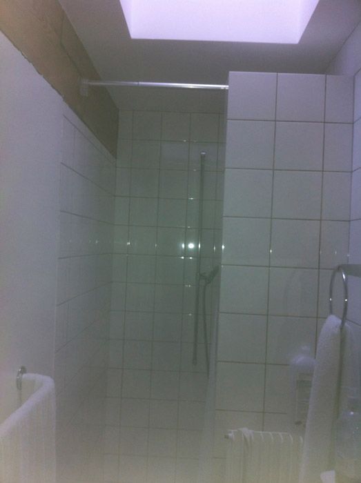 Une salle de bain avec du carrelage blanc et une cabine de douche