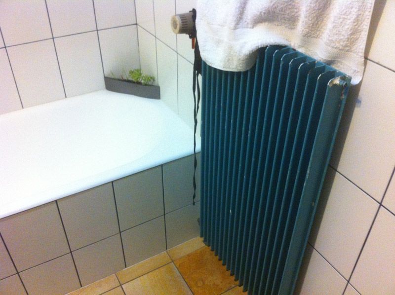 Un radiateur bleu dans une salle de bain à côté d'une baignoire